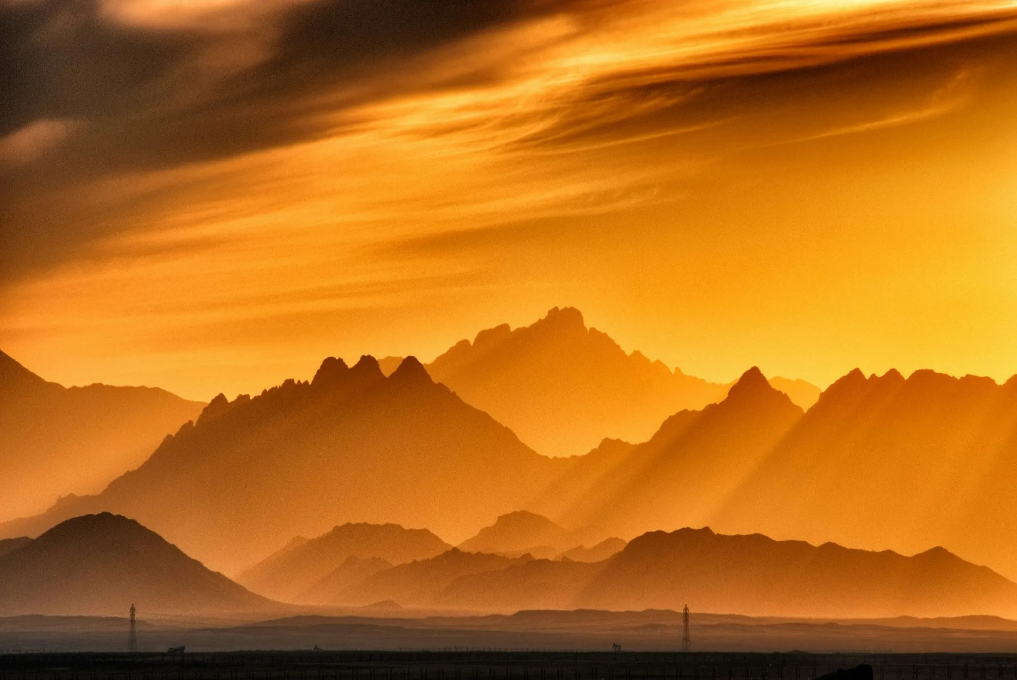 Layered mountain ridges in orange evening haze